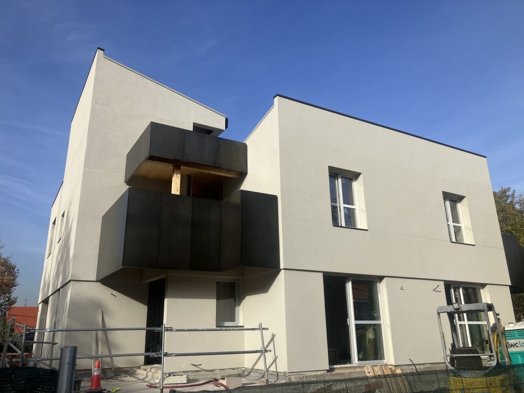 Fachada moderna de edificio en construcción con diseño minimalista y balcón negro, ideal para reformas y construcciones.