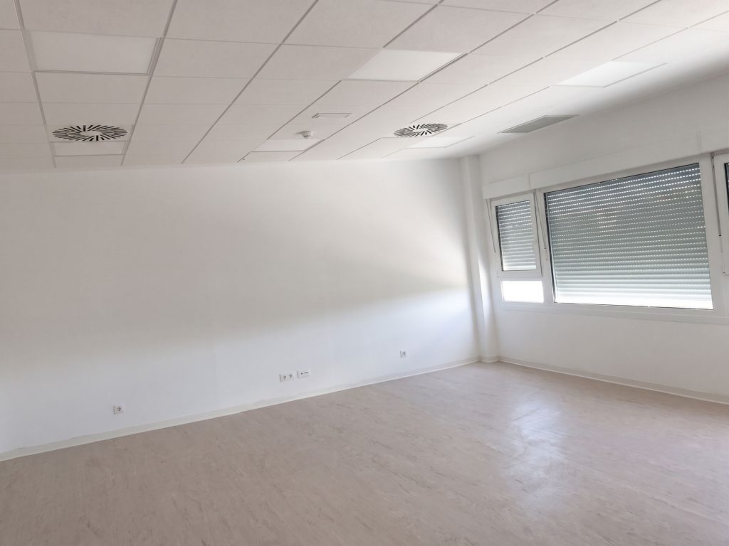 Sala vacía con paredes blancas y ventanas amplias, ideal para reformas y construcciones en Apro CM.