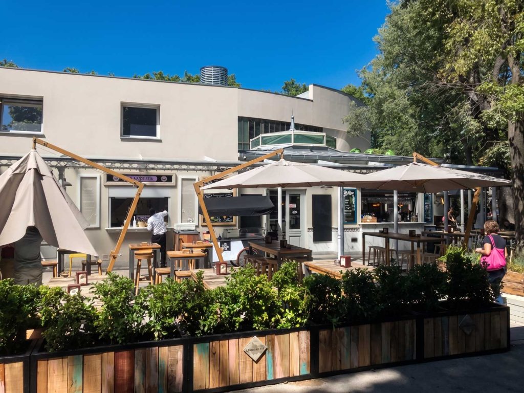 Terraza de restaurante moderna con sombrillas y muebles de madera, ideal para reformas y construcción en espacios exteriores.