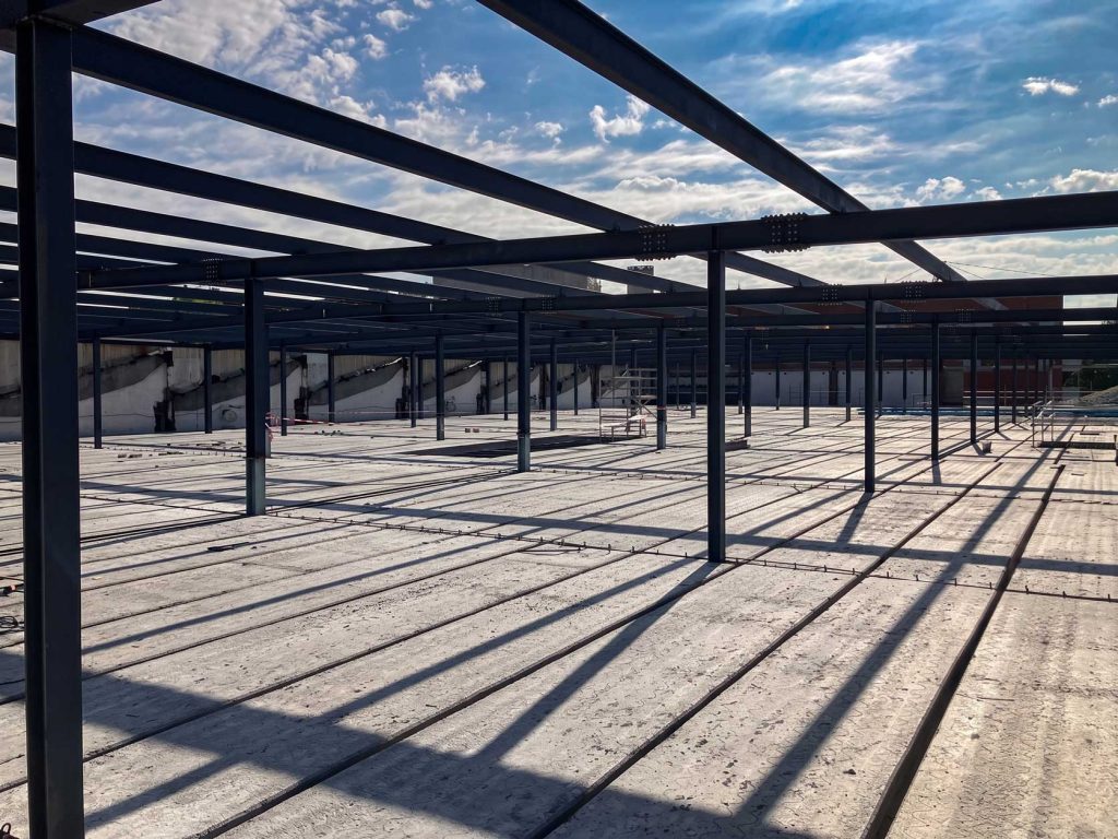 Estructura metálica en construcción con sombras en el suelo, ideal para reformas y proyectos de Apro CM.