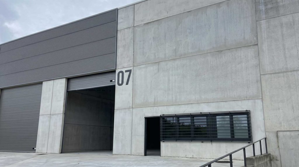 Fachada de edificio industrial moderno con entrada amplia y número 07, ideal para reformas y construcciones.