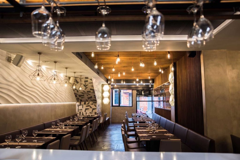 Interior moderno de restaurante con iluminación cálida, mesas elegantes y diseño contemporáneo, ideal para reformas.